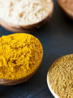 various spices in wooden spoons and bowls